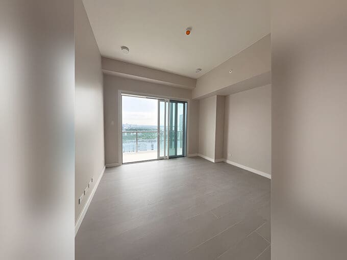 Empty living area with floor-to-ceiling window and light wood flooring, corner 2BR suite at Aruga Residences, Mactan