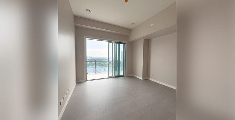 Empty living area with floor-to-ceiling window and light wood flooring, corner 2BR suite at Aruga Residences, Mactan