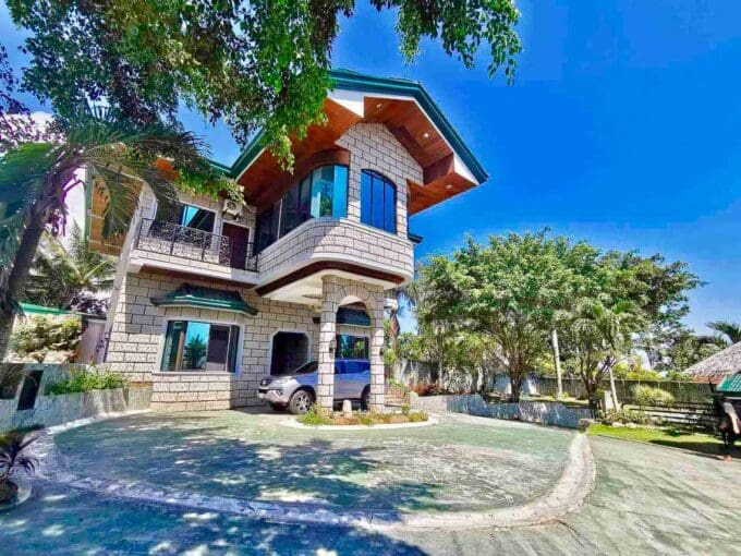 Two-storey stone-clad house with circular driveway and garden at the 6BR house and lot with pool for sale in Maghaway, Talisay