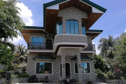 Front elevation of the two-storey stone-clad house at the 6BR house and lot with pool for sale in Maghaway, Talisay