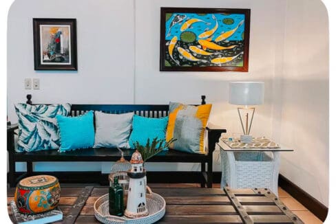 Seating area with framed artwork and low wooden table at the house and lot for sale in Maghaway, Talisay