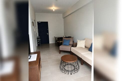 Living area with sofa, armchair and dining set at the furnished 1BR condo for sale in Boracay Newcoast