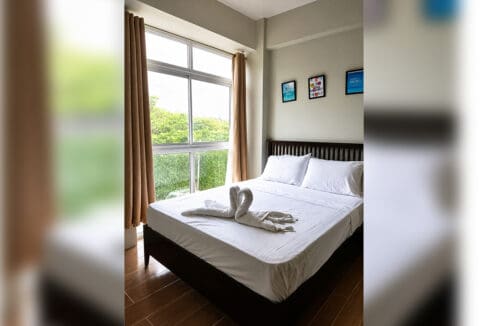Bedroom with full-height window and garden outlook at the furnished 1BR condo for sale in Boracay, Oceanway Residences