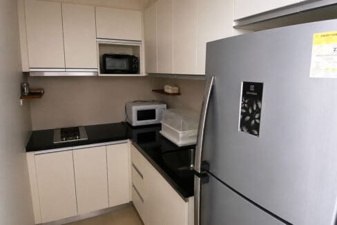 Kitchen counter with gas cooktop, range hood, microwave and refrigerator at the 1BR condo for sale in Boracay