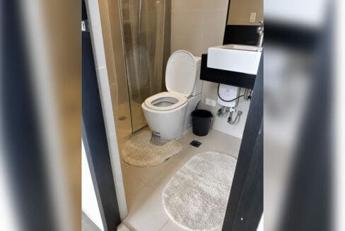 Bathroom with glass shower enclosure, water heater and wall-hung basin at the 1BR condo for sale in Boracay