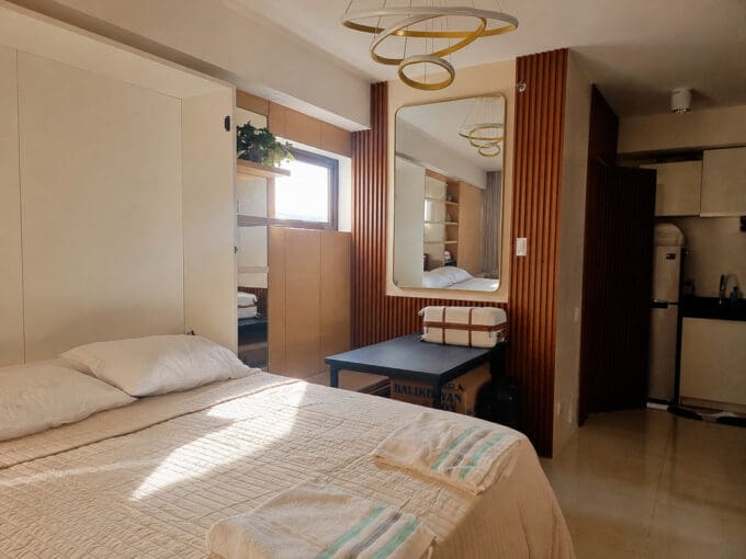 Studio interior with slatted wood feature wall, bed and kitchenette at the furnished studio for sale in Mabolo, Cebu City