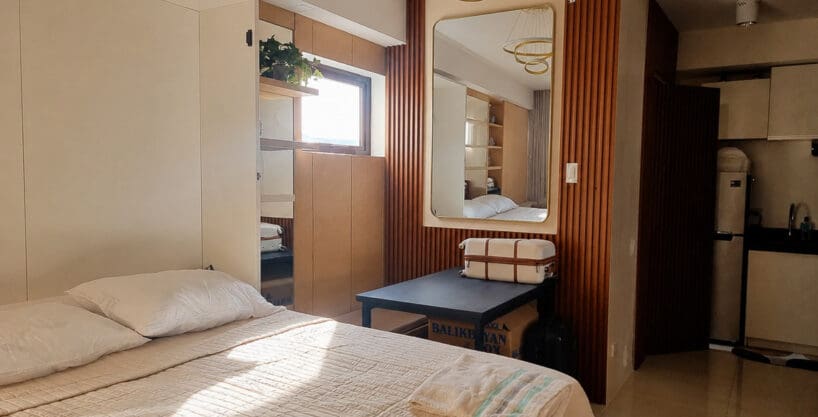 Studio interior with slatted wood feature wall, bed and kitchenette at the furnished studio for sale in Mabolo, Cebu City
