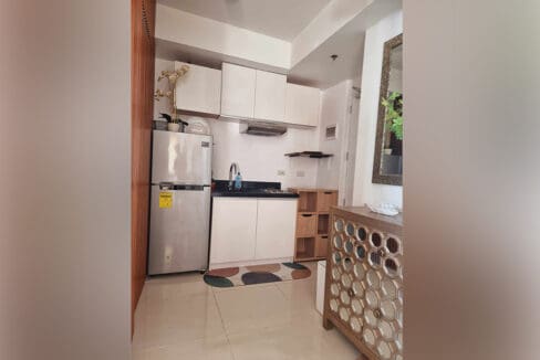 Kitchen with refrigerator, overhead cabinets and range hood at the furnished studio for sale in Mabolo, Cebu City