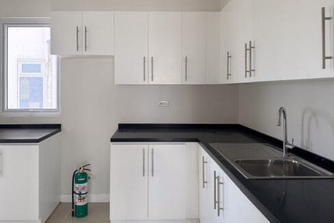 Fitted kitchen with white cabinetry, black granite counters and a double-bowl sink at the condo for sale at Sedona Parc