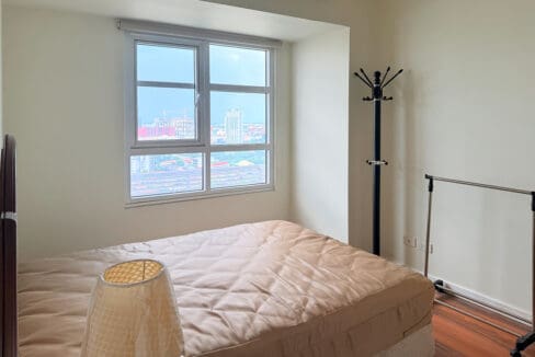Bedroom with dark wood-look laminate flooring and a city-facing window on the 22nd floor