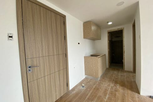 Entry area with built-in kitchen counter, overhead cabinets and the bathroom doorway