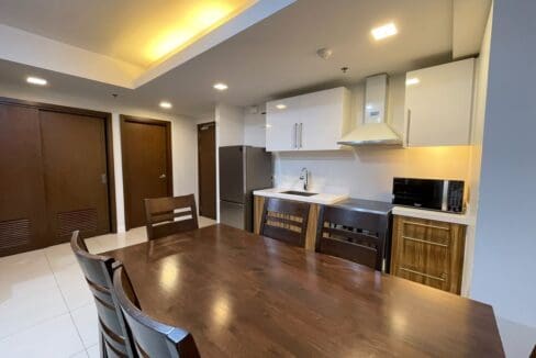 Dining table and kitchen with range hood and stainless refrigerator