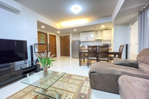 Living and dining area with wall-mounted flatscreen TV and kitchen beyond