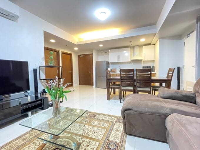 Living and dining area with wall-mounted flatscreen TV and kitchen beyond