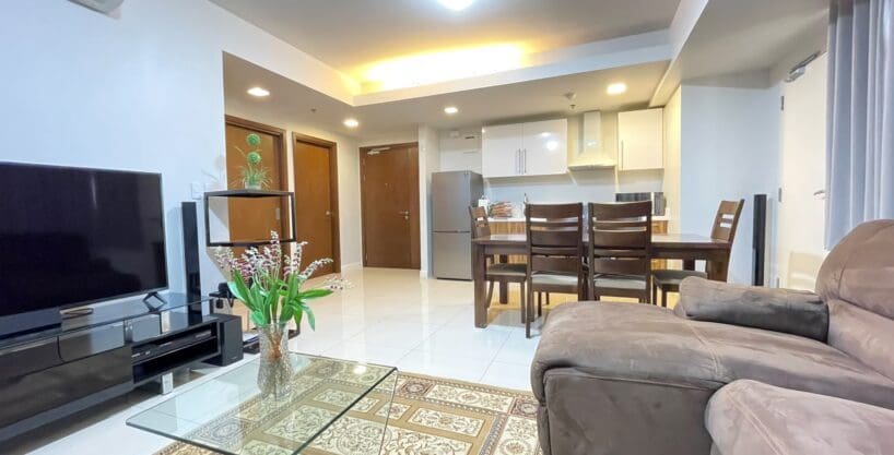 Living and dining area with wall-mounted flatscreen TV and kitchen beyond