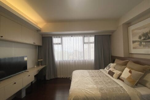 Bedroom television and desk with overhead cabinets beneath full-length curtains