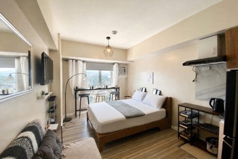 Studio seen from the kitchen end, with the sofa, bed and window bay in one open run