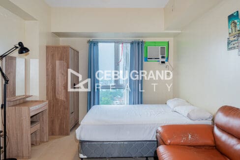 Bed at the window end, with a timber wardrobe and dressing table alongside