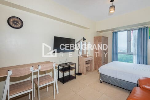 Wall-mounted television, study desk with two chairs and the bed by the window