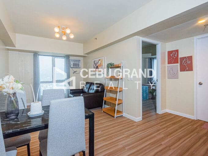Living and dining area of the 1BR corner unit at Avida Riala Tower 4, with the bedroom door beyond
