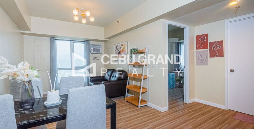 Living and dining area of the 1BR corner unit at Avida Riala Tower 4, with the bedroom door beyond