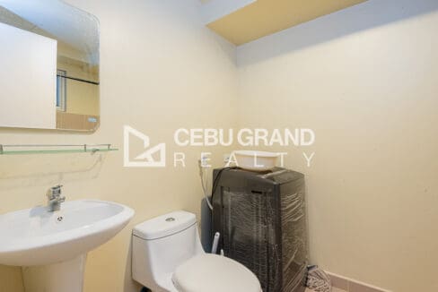 Bathroom with pedestal basin, mirror and the washing machine beside the toilet