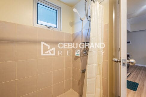 Tiled shower area with water heater and curtain in the bathroom