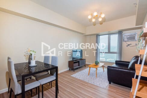 Dining table for four beside the living area, with the window wall behind the television