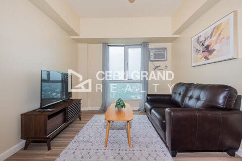 Leather sofa and timber coffee table facing the television, with the city view through the window