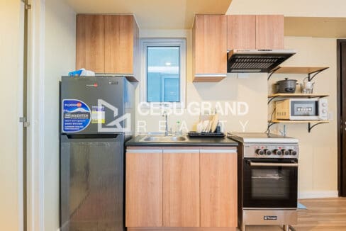 Kitchen counter with sink, gas range, refrigerator, microwave and rice cooker on open shelves