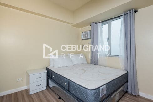 Double bed with bedside cabinet and window-type air conditioning in the bedroom