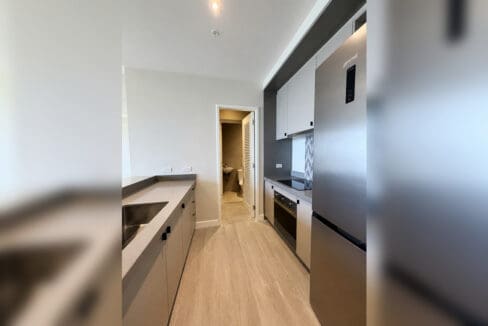 Galley kitchen with stainless refrigerator and built-in oven