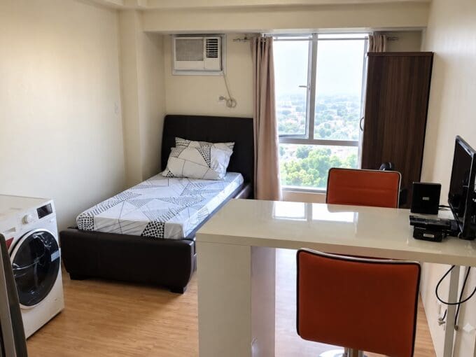 Studio living and sleeping area with a breakfast counter and washing machine at Avida Towers, Cebu IT Park
