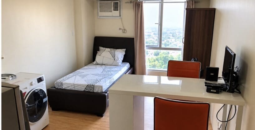 Studio living and sleeping area with a breakfast counter and washing machine at Avida Towers, Cebu IT Park
