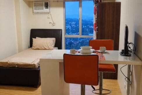 Breakfast counter set for two beside the bed, with the city visible through the window at dusk