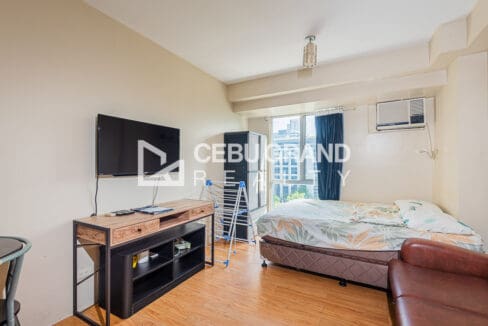 Flat-screen television on a timber console facing the bed in the studio