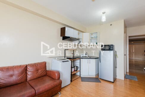 Kitchenette with white cabinets, range hood, sink, refrigerator and washing machine by the entry