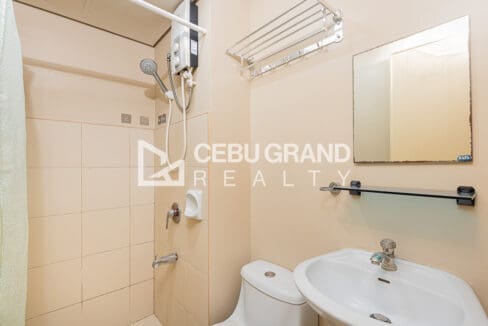 Bathroom with a tiled shower area, water heater, mirror and glass shelf