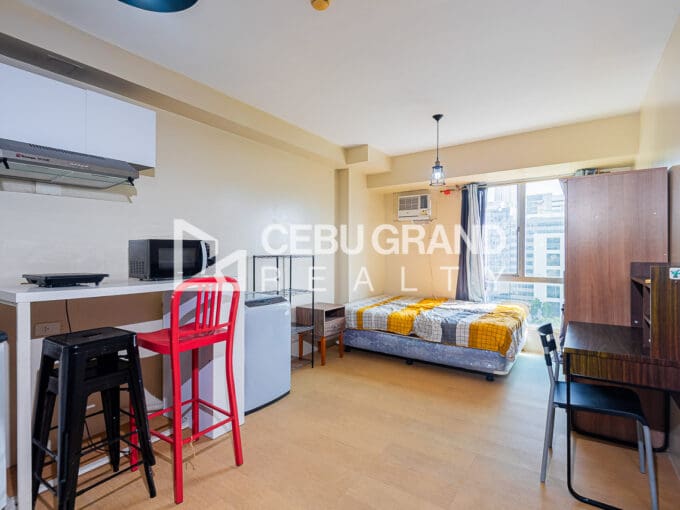 Furnished studio at Avida Tower 2 with the kitchen counter, bar stools and the bed by the window