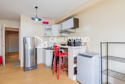 Kitchen counter with bar stools, refrigerator and washing machine by the entry
