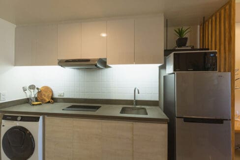 Kitchen with pale cabinetry, stone-finish counter, induction hob and built-in washer-dryer