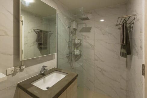 Bathroom with glass-enclosed rain shower and marble-look tiling