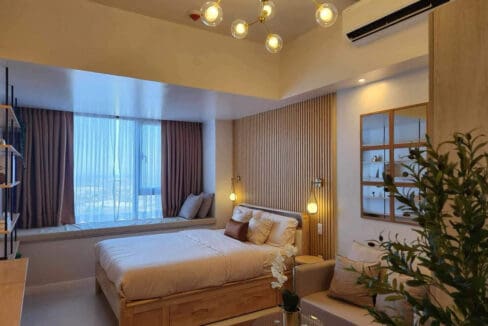 Bed beside the cushioned window nook with sea views, 36th floor studio at Mandani Bay Suites