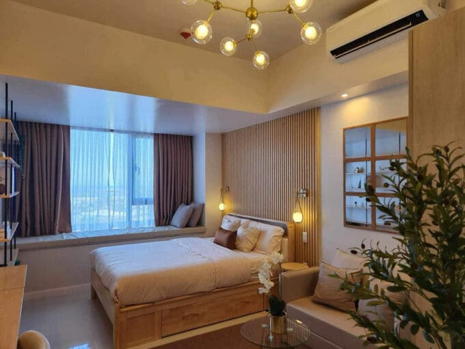 Bed beside the cushioned window nook with sea views, 36th floor studio at Mandani Bay Suites