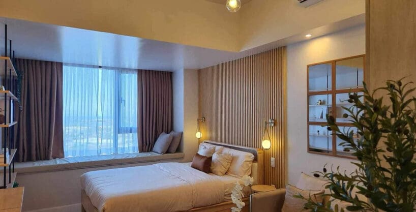 Bed beside the cushioned window nook with sea views, 36th floor studio at Mandani Bay Suites
