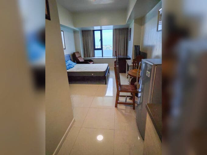 Furnished studio for rent at Mandani Bay Suites Tower 2 with bed, recliner and a window facing the sea, Mandaue City