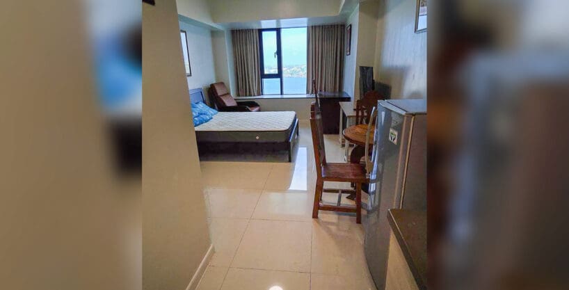 Furnished studio for rent at Mandani Bay Suites Tower 2 with bed, recliner and a window facing the sea, Mandaue City