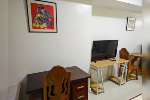 Timber work desk with drawers and a flat-screen TV on a trestle table, with framed artwork