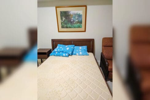 Double bed with timber headboard, bedside table and recliner armchair