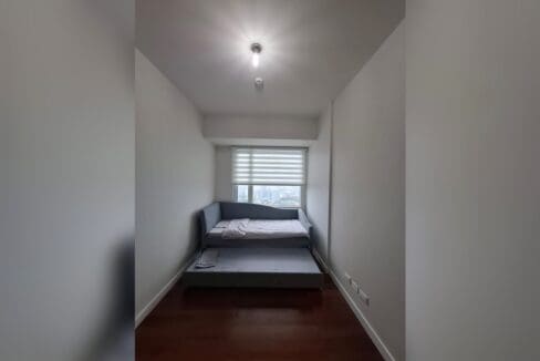 Bedroom with a daybed and pull-out trundle beneath a window over the city.